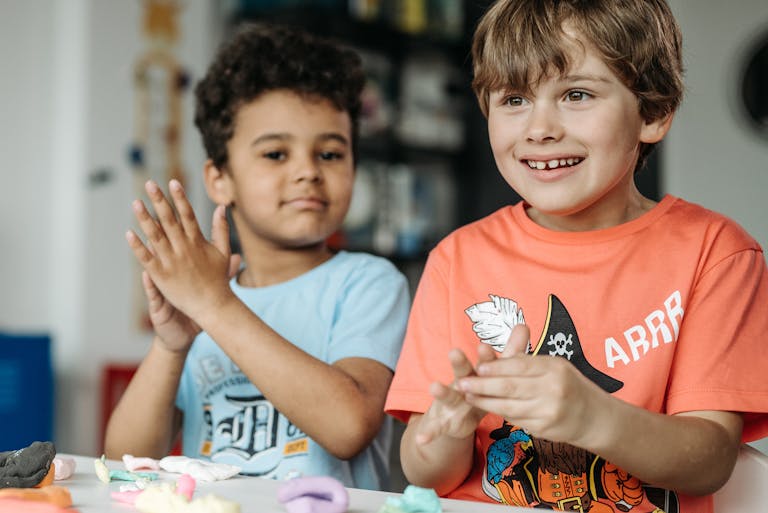 Two joyful children participating in a creative art workshop with clay at school.