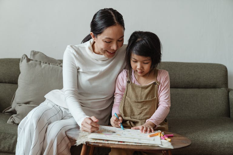 Happy smiling Asian mother and cute little girl sitting on sofa and coloring picture with multicolored crayons Build Strong Connections With Your Preschooler