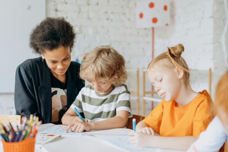 Teacher guides children in a creative classroom activity, focusing on learning and interaction. Building Relationships in Early Childhood