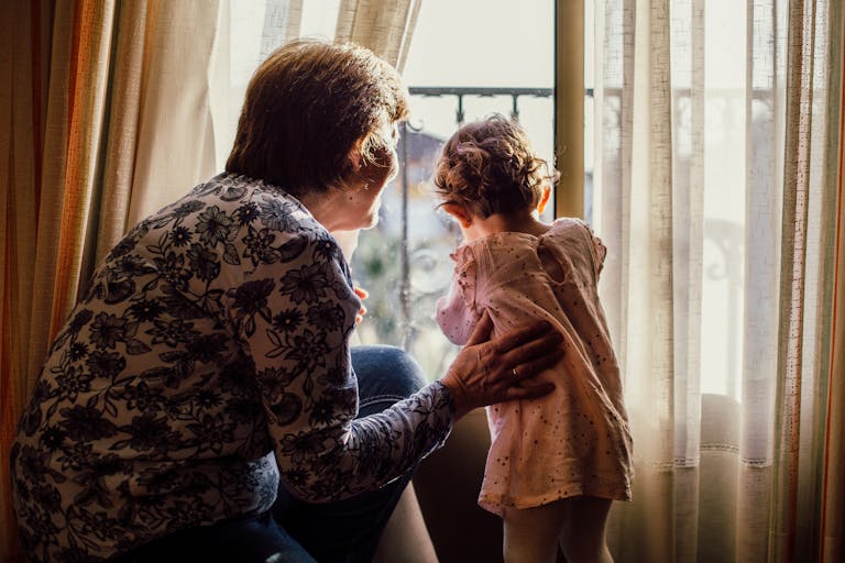 A loving moment between grandmother and grandchild near a window filled with sunlight. simply being there for your grandchildren