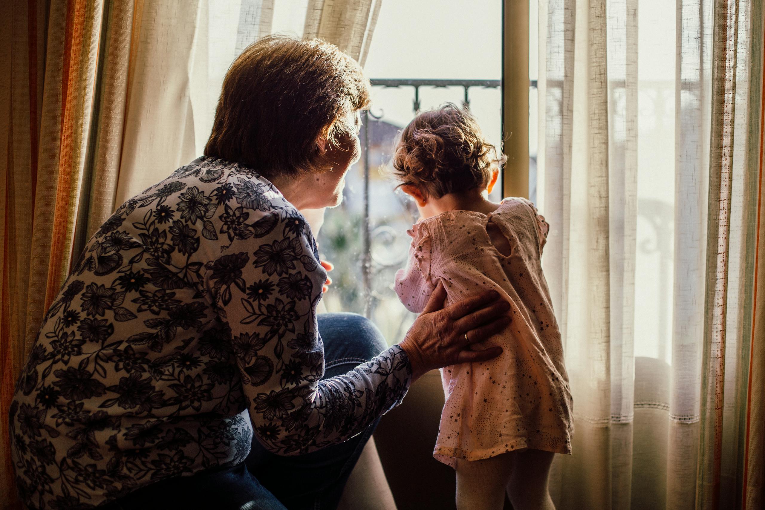 A loving moment between grandmother and grandchild near a window filled with sunlight. simply being there for your grandchildren